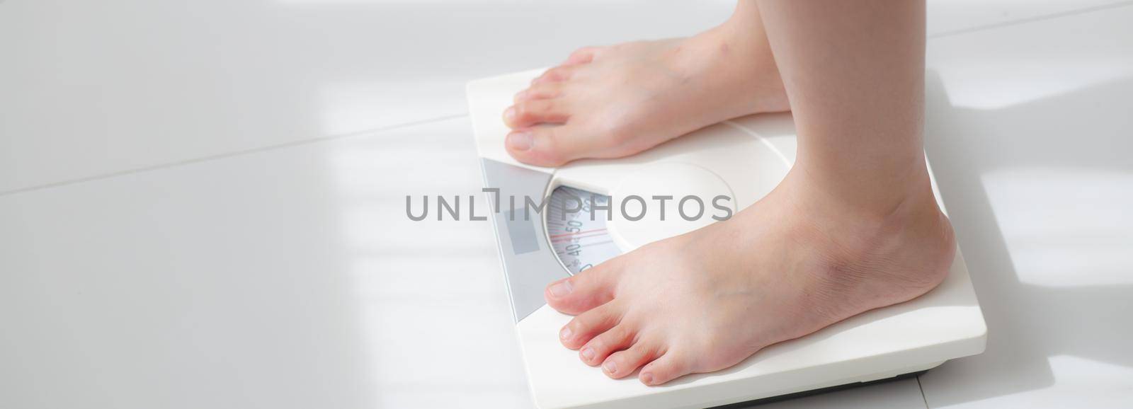 Lifestyle activity with leg of woman stand measuring weight scale for diet with barefoot, closeup foot of girl slim weight loss measure for food control, healthy care concept, banner website. by nnudoo