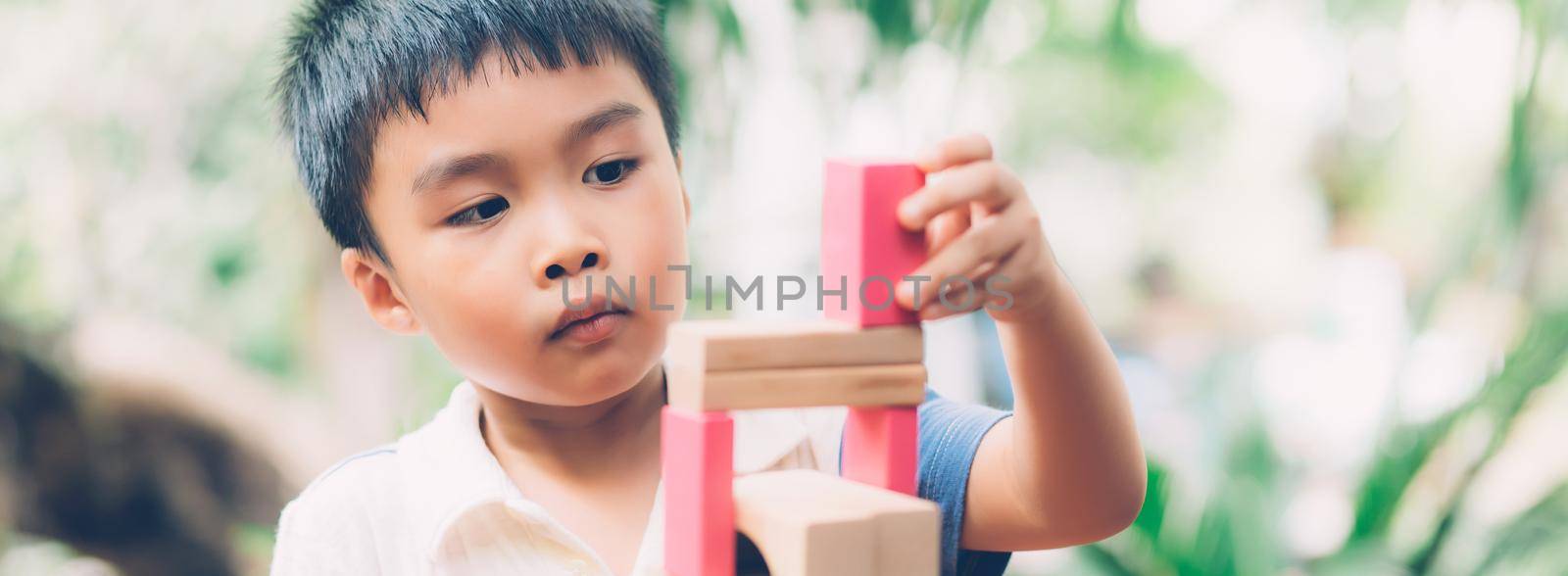 Asian young boy playing wooden block toy on table for creative and development, happy child learn skill for activity puzzle and creativity for game on desk at home, education concept, banner website.