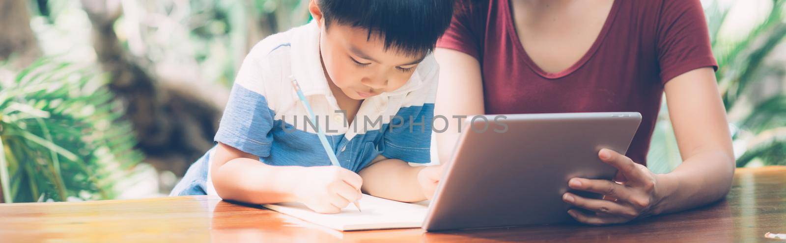 Son using digital tablet computer for study and learn to internet online with mother together, education from home, family recreation, mom teach boy and homework, lifestyle concept, banner website. by nnudoo