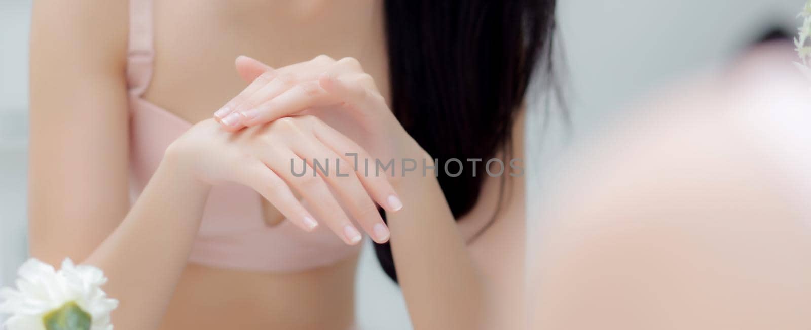 Closeup hand of young woman looking mirror applying cream on hand and message, beauty girl applying body lotion skin care for health, treatment and cosmetic with moisturizer, banner website.