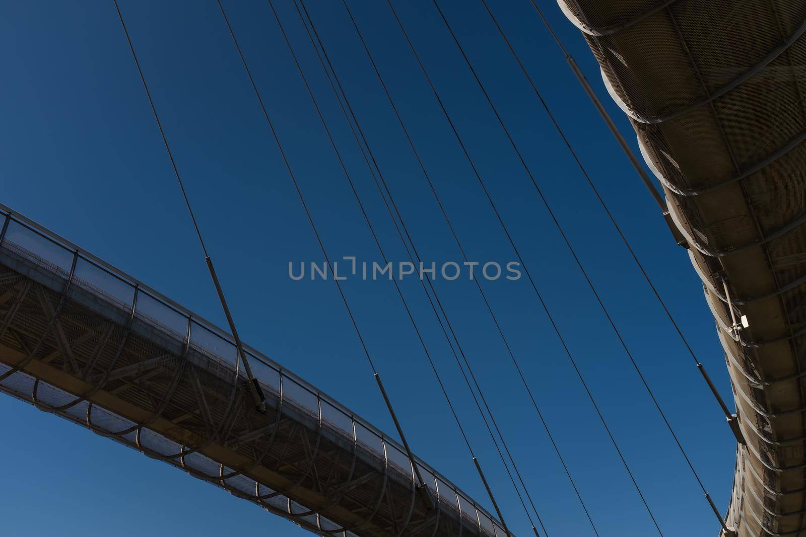 Directly below view of the Ponte del Mare (Bridge of the Sea) in Pescara, Italy. Partial view against a blue sky. by Riccarduska