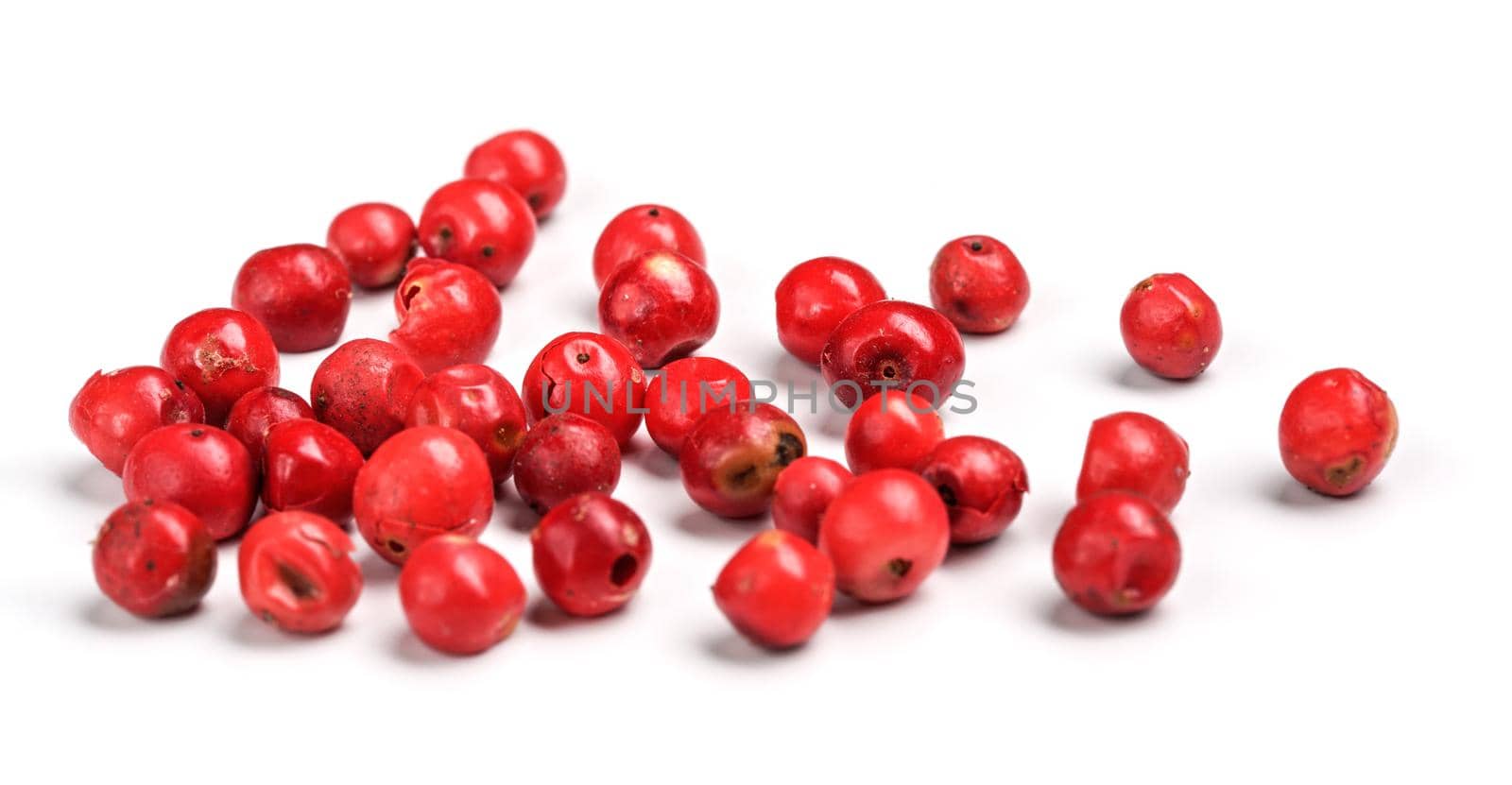 Red or Pink peppercorn scattered on board, closeup photo isolated with white background by Ivanko