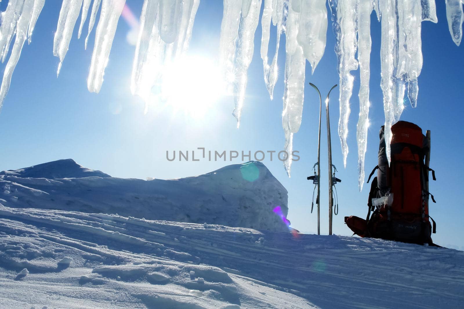 skier's backpack and skis in the snow. Icicles against the sky.