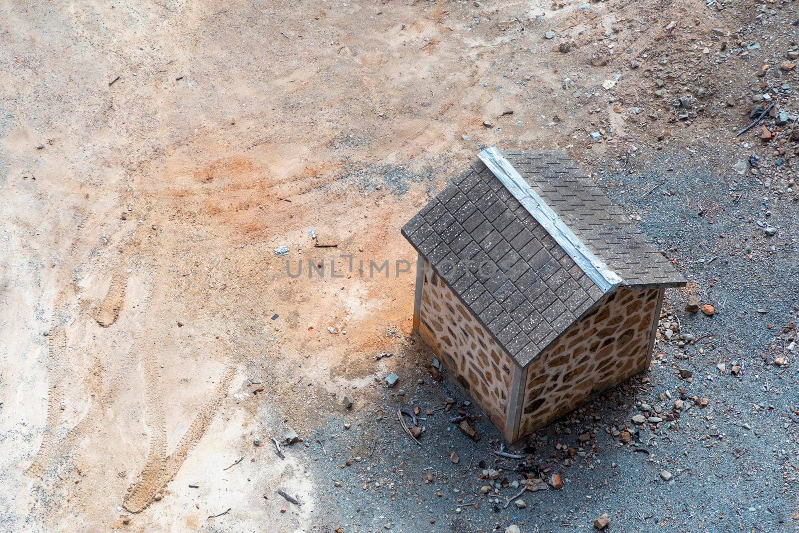 A small brown brick building with tiled roof on dry dirt surrounded by rocks