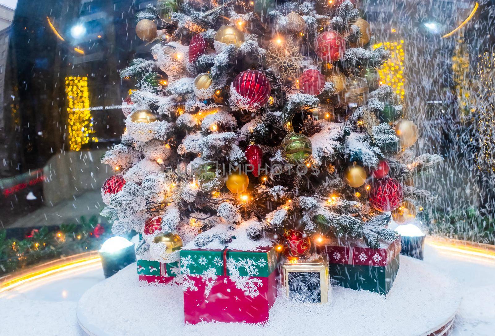 A Christmas tree with gifts underneath, covered with freshly fallen snow.