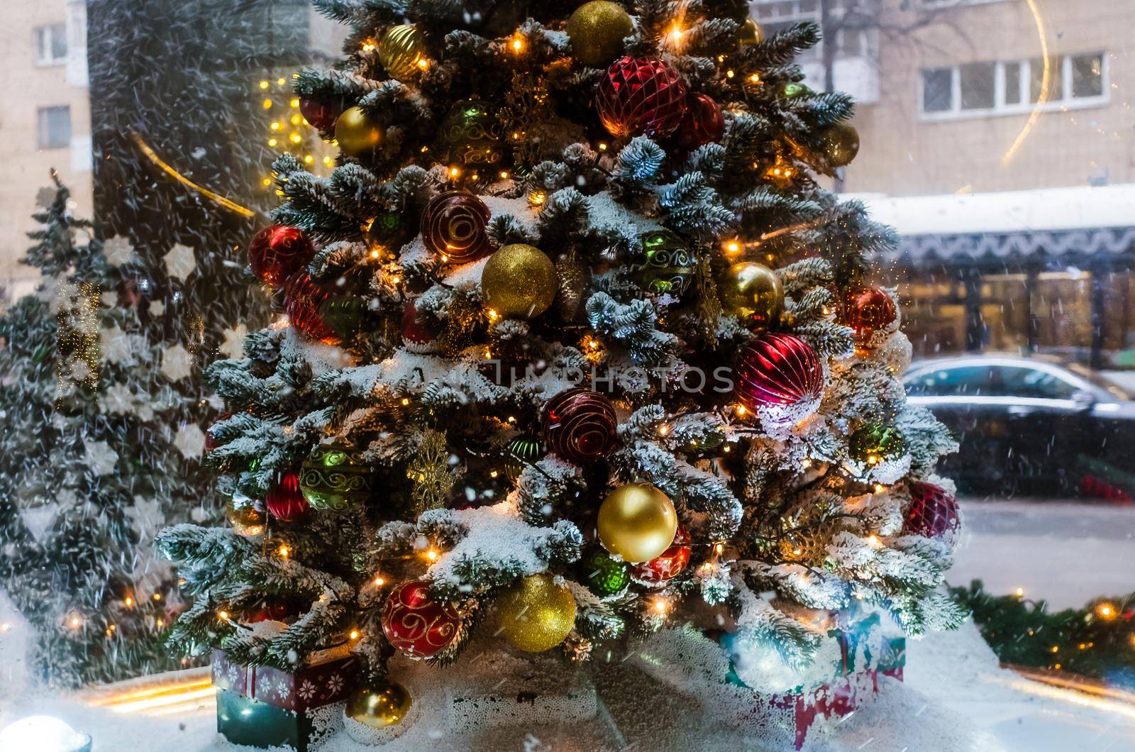 A Christmas tree with gifts underneath, covered with freshly fallen snow.