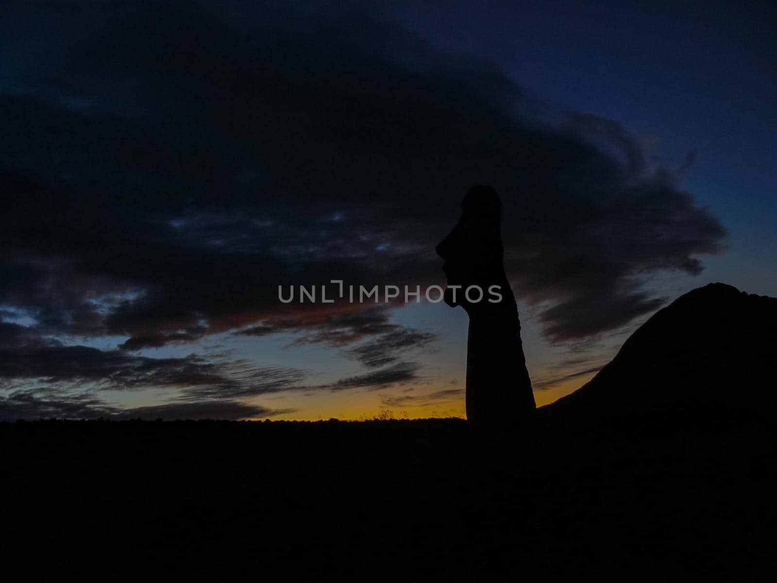 Statues of Easter Island in the background of the sunset. The melting of the Easter statue in the sunlight of the sunset.