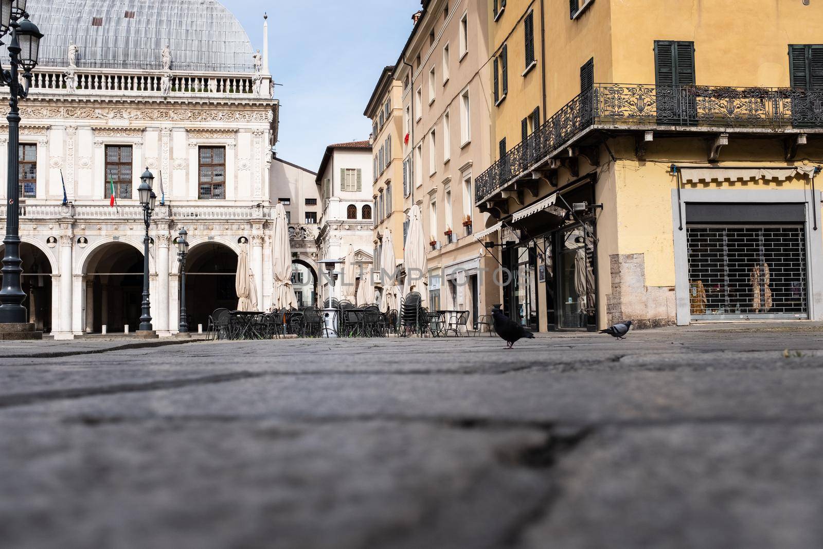 Street-level view of an unusually empty Italian square on Saturday morning: some incredulous pigeons looking for food in the deserted main square of Brescia. The city as the entire country is lockdown at least until May, in a bid to slow the spread of coronavirus.