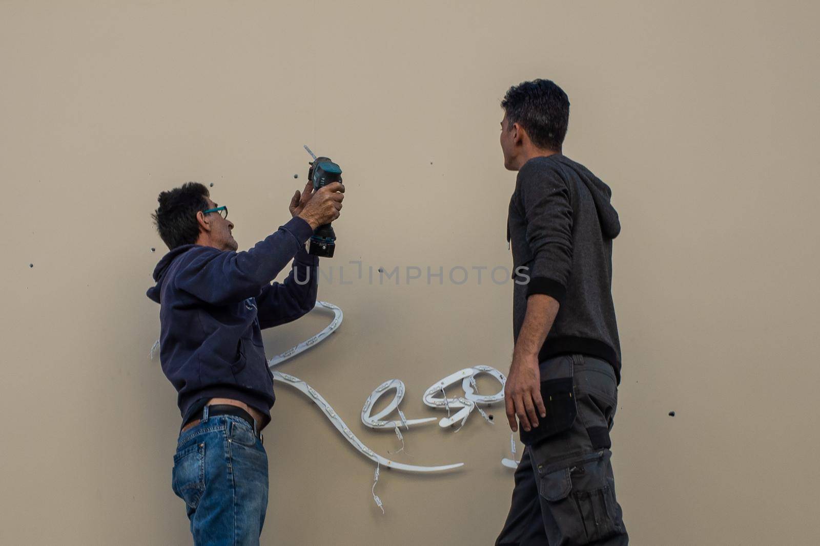 April 22, 2019, Limassol, Cyprus. Two workers are installing a cafe sign on a street in the city of Limassol.