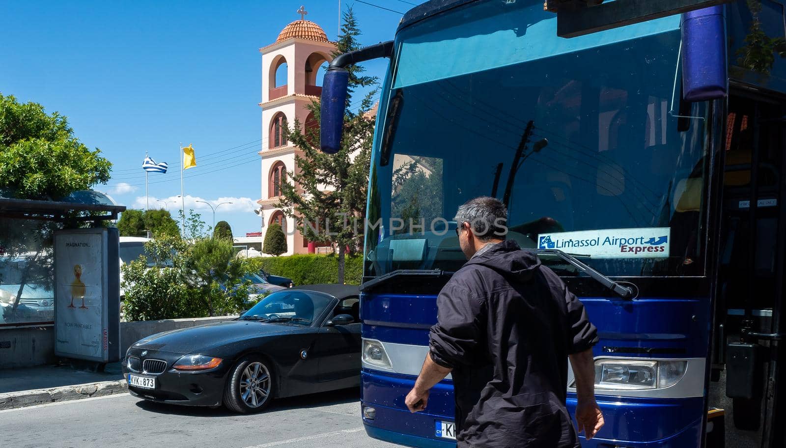 April 22, 2019, Limassol, Cyprus. Blue bus on the background of the bell tower of the Christian Church at the Limassol bus station