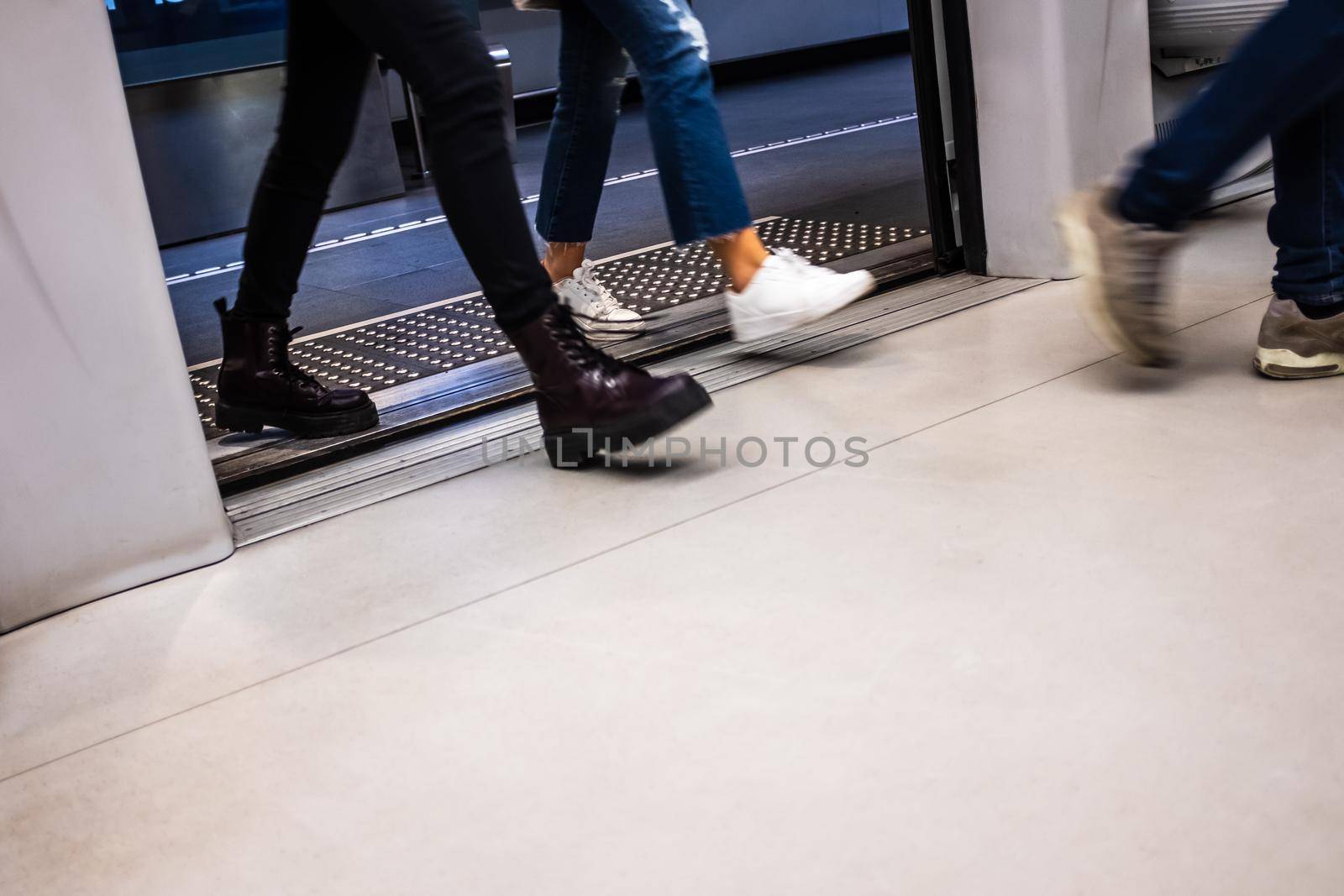 Motion blurred passengers entering wagon door on a subway station in Brescia (Lombardy, Italy). Tactile paving to guide blind people, installed at the edge of platform, is visible in background. Copy space for text.