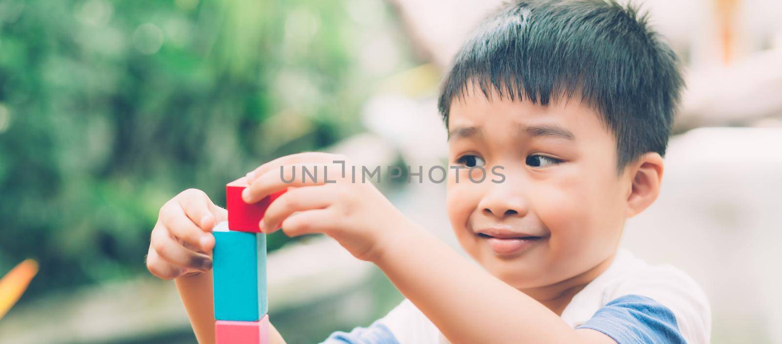 Asian young boy playing wooden block toy on table for creative and development, happy child learn skill for activity puzzle and creativity for game on desk at home, education concept, banner website. by nnudoo