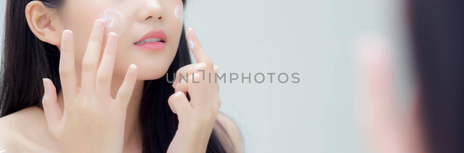 Beautiful young asian woman look at mirror of checking face with skin care and cosmetic and hygiene, beauty girl happy clean facial with cream or lotion and for health, banner, website.