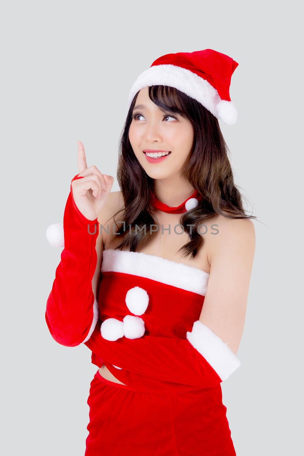 Beautiful portrait young asian woman Santa costume smiling present pointing something in xmas holiday, model asia girl cheerful and happiness celebrating in Christmas isolated on white background. by nnudoo