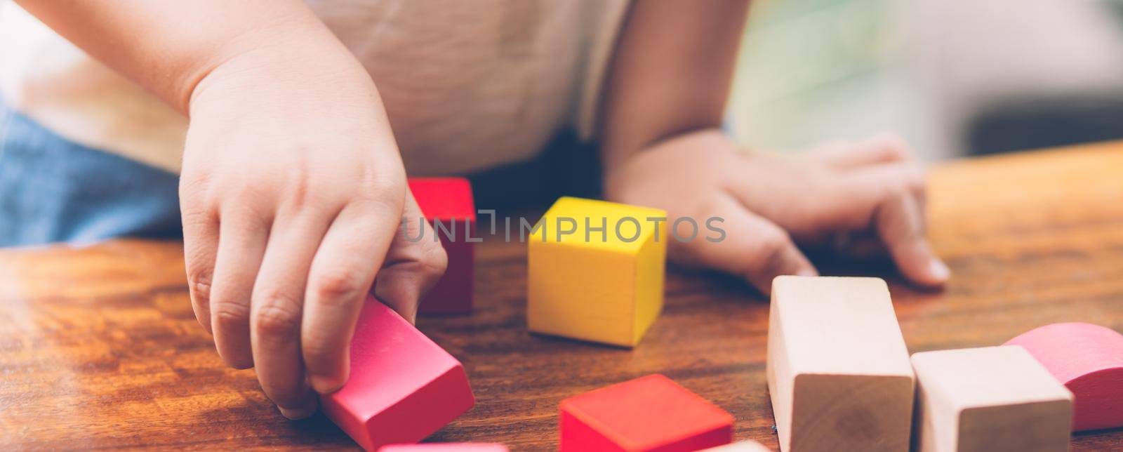 Closeup hand of boy playing wooden block toy on table for creative with enjoy, happy child learn skill for activity puzzle and creativity for game on desk at home, education concept, banner website.