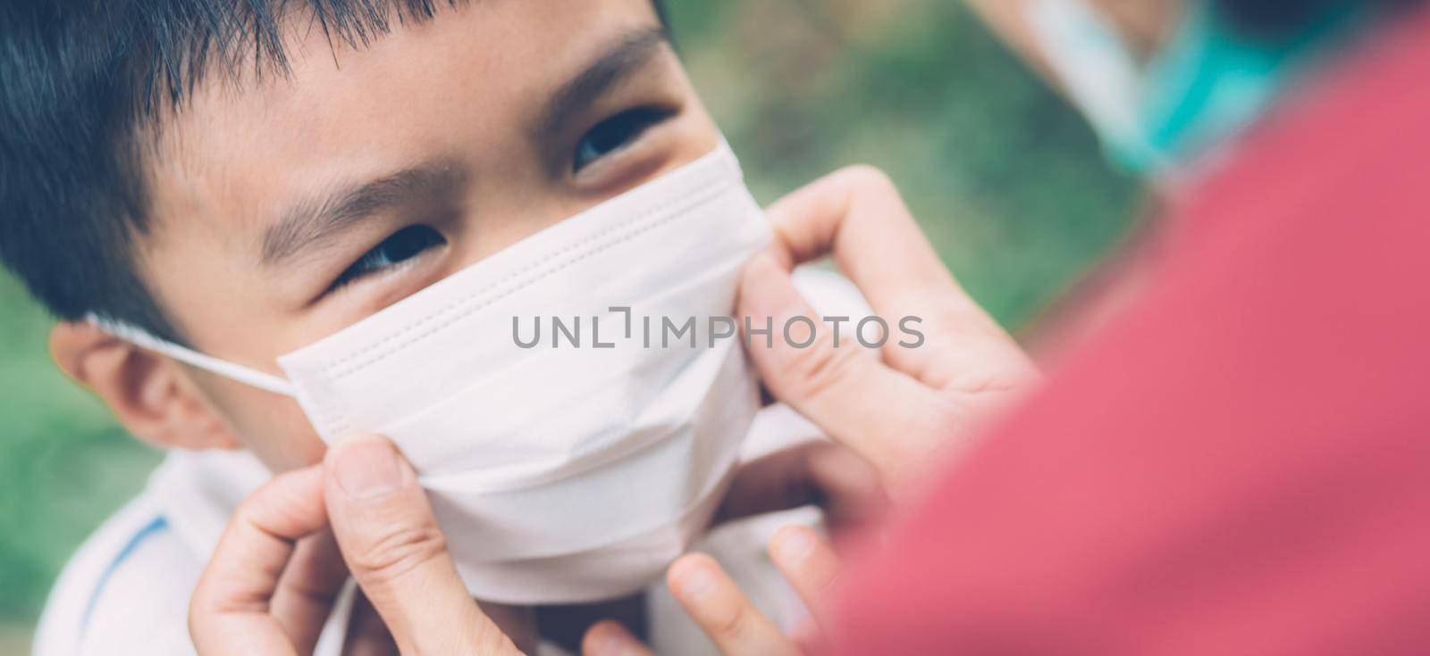 Mother take care son with face mask for protection disease flu or covid-19 outdoors, mom wearing on medical mask with child safety for protect outbreak of pandemic, medical concept, banner website. by nnudoo