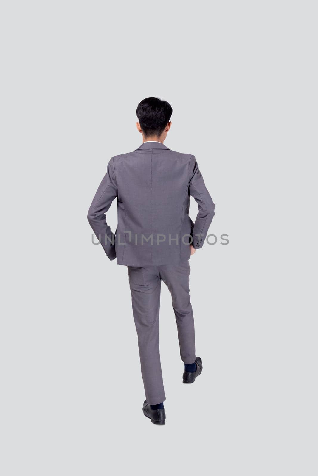 Back view young asian business man in suit walking isolated on white background, portrait of executive or manager, happy businessman handsome and smart, male with confident for success in studio. by nnudoo