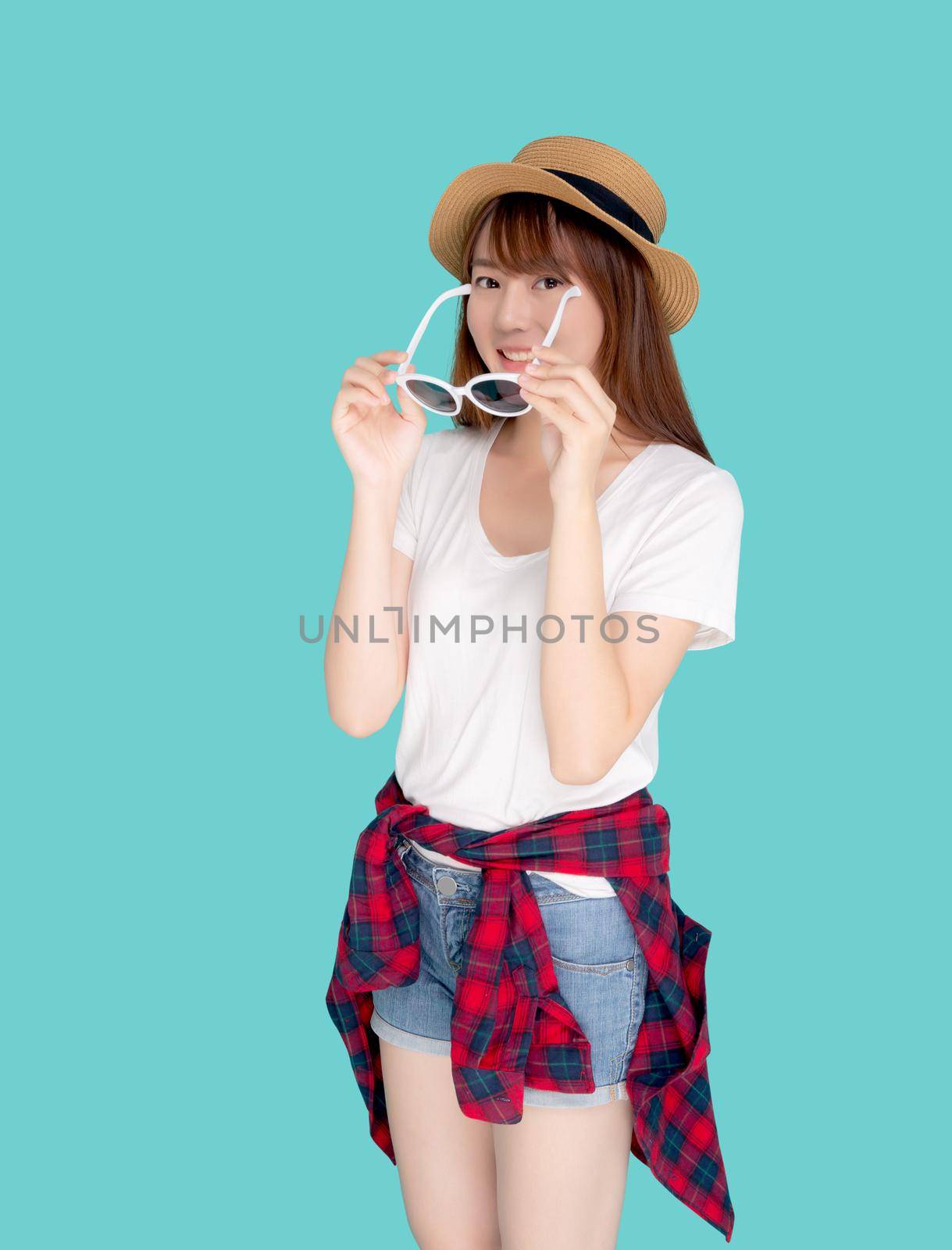 Beautiful portrait young asian woman wear hat and holding sunglasses smiling confident enjoy journey summer trip in vacation isolated on blue background, tourist asia girl cheerful with travel.