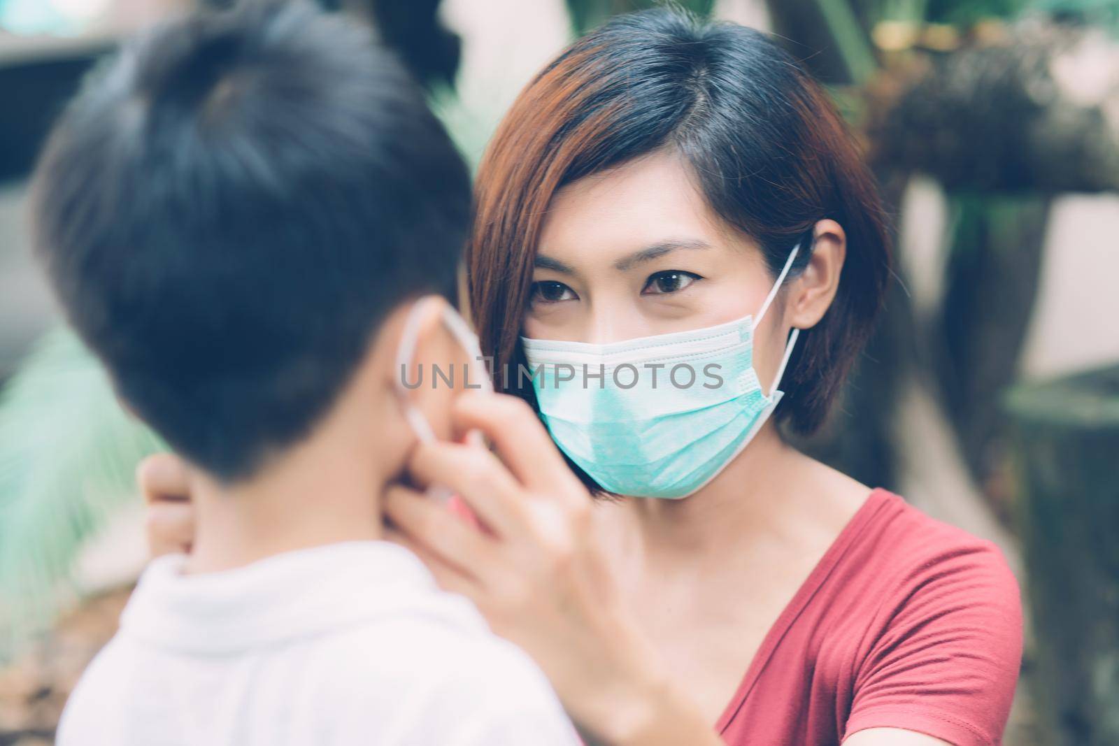 Mother take care son with face mask for protection disease flu or covid-19 outdoors, mom wearing on medical mask with child safety for protect outbreak of pandemic in public, medical concept.