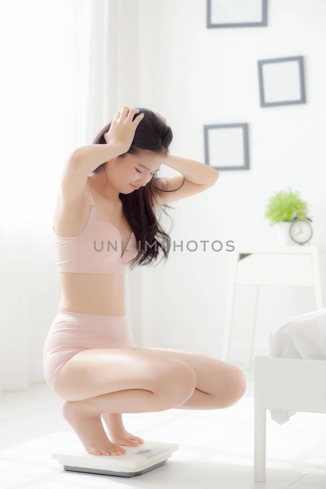 Beautiful young asian woman in underwear sitting on scales for control weight loss with fail and sad emotion at room, beauty girl have problem and frustrated with unsuccessful for diet.