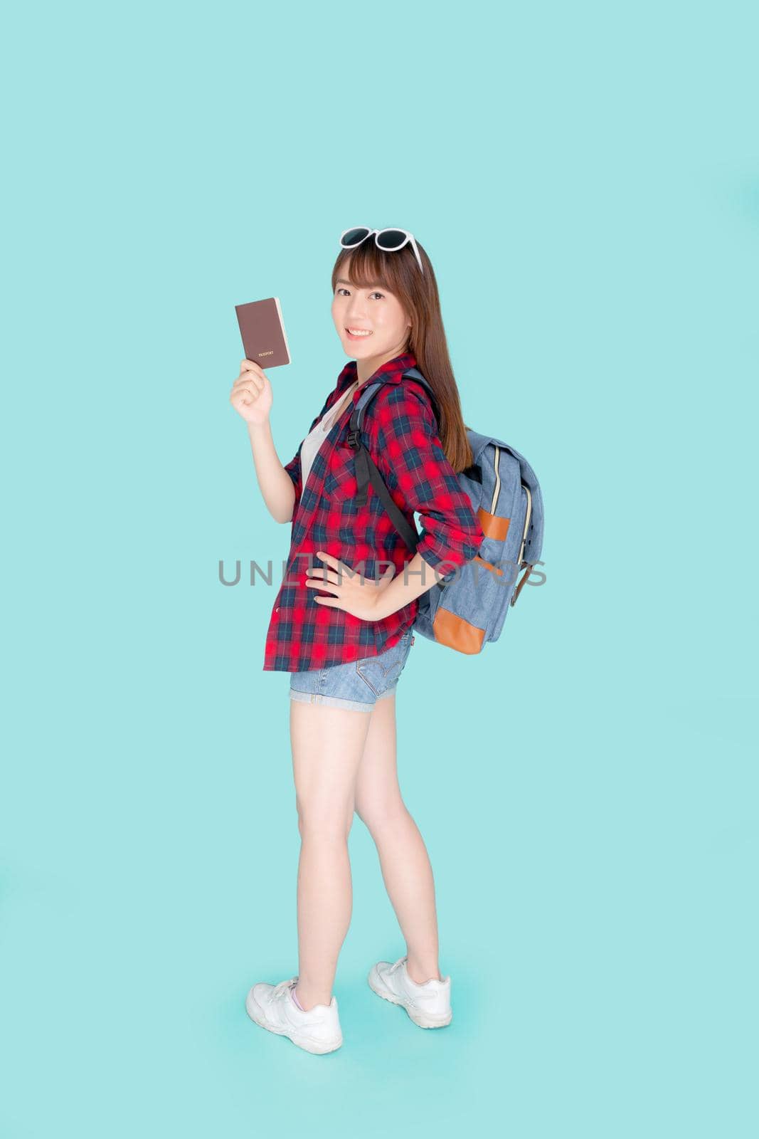 Beautiful portrait young asian woman wear sunglasses on head and backpack smile confident enjoy summer holiday isolated blue background, model girl fashion hipster holding passport, travel concept. by nnudoo
