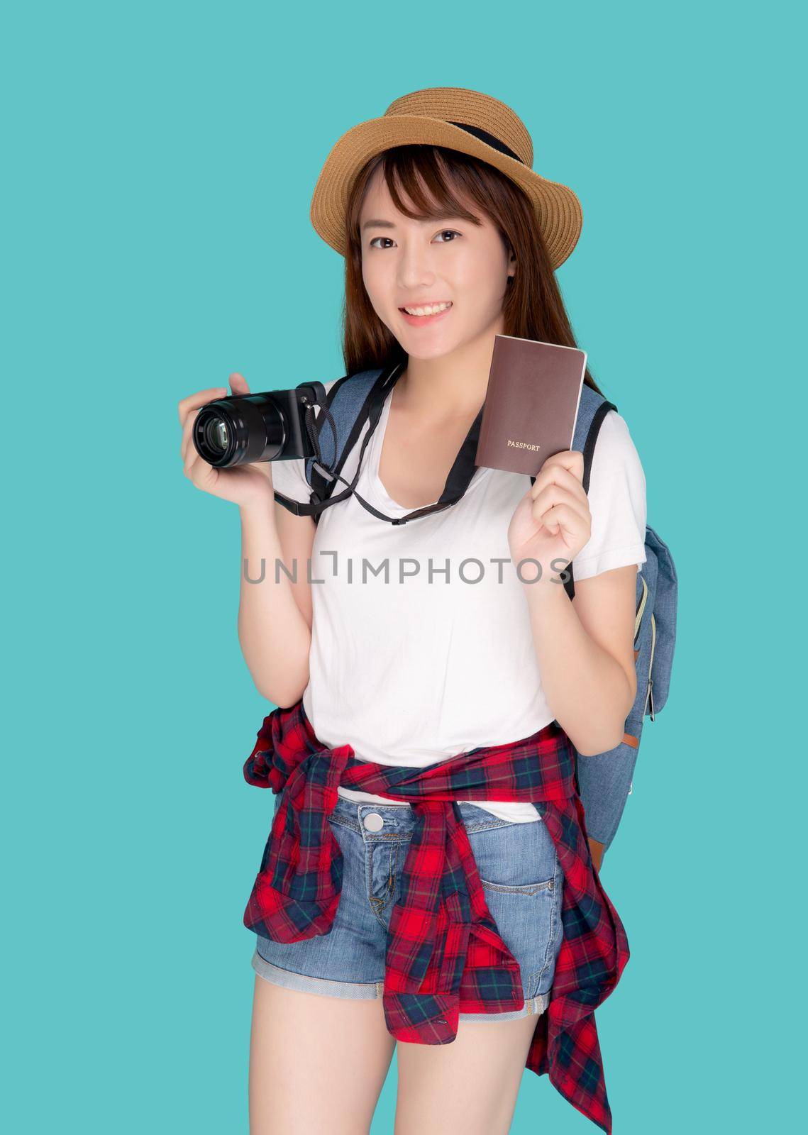 Beautiful portrait young asian woman wear hat smile confident holding passport and camera with travel summer trip in vacation isolated blue background, model tourist asia girl cheerful with journey. by nnudoo