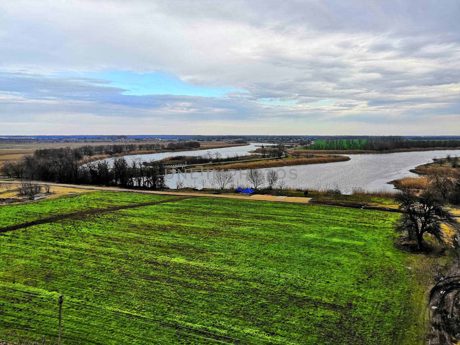 View of green field and river, spring morning by Bezdnatm