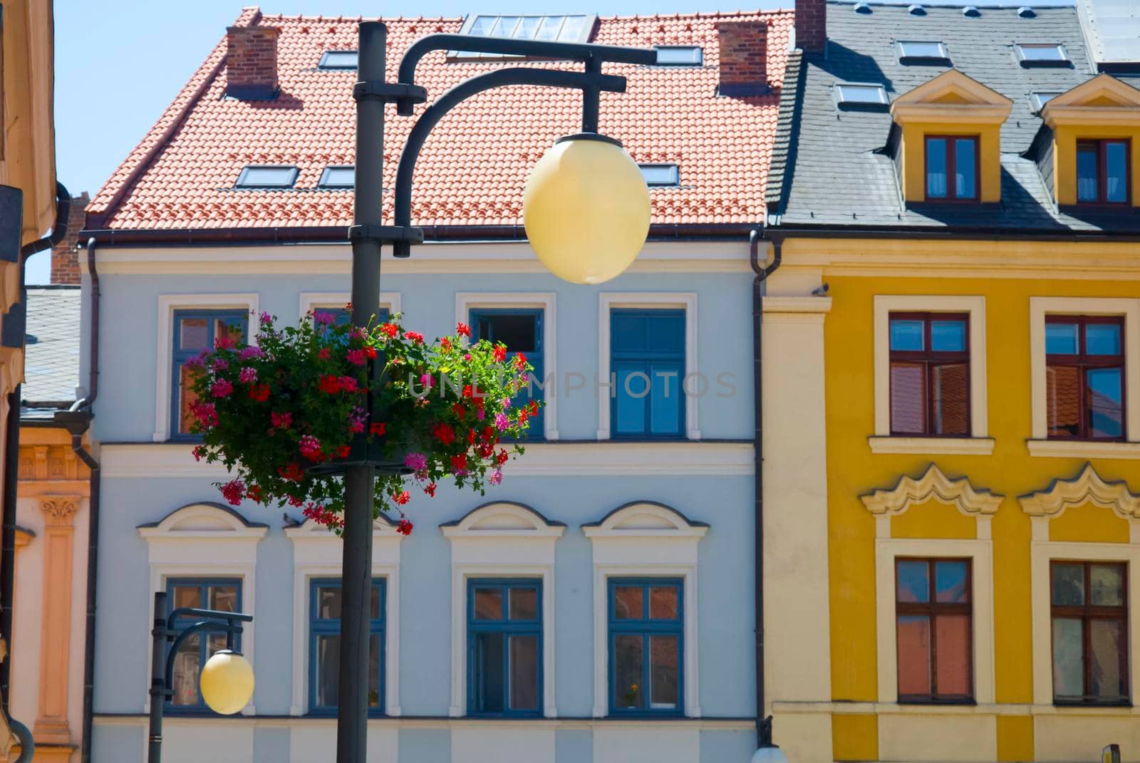 Blue and yellow houses facade with lamp and flower pot, summer, Czech Republic
