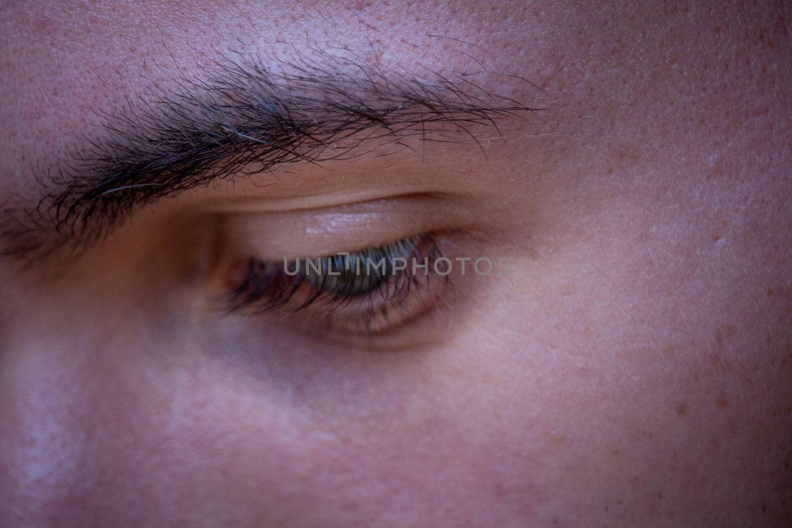 Close up of eye and eyebrow with darker skin and eye looking down