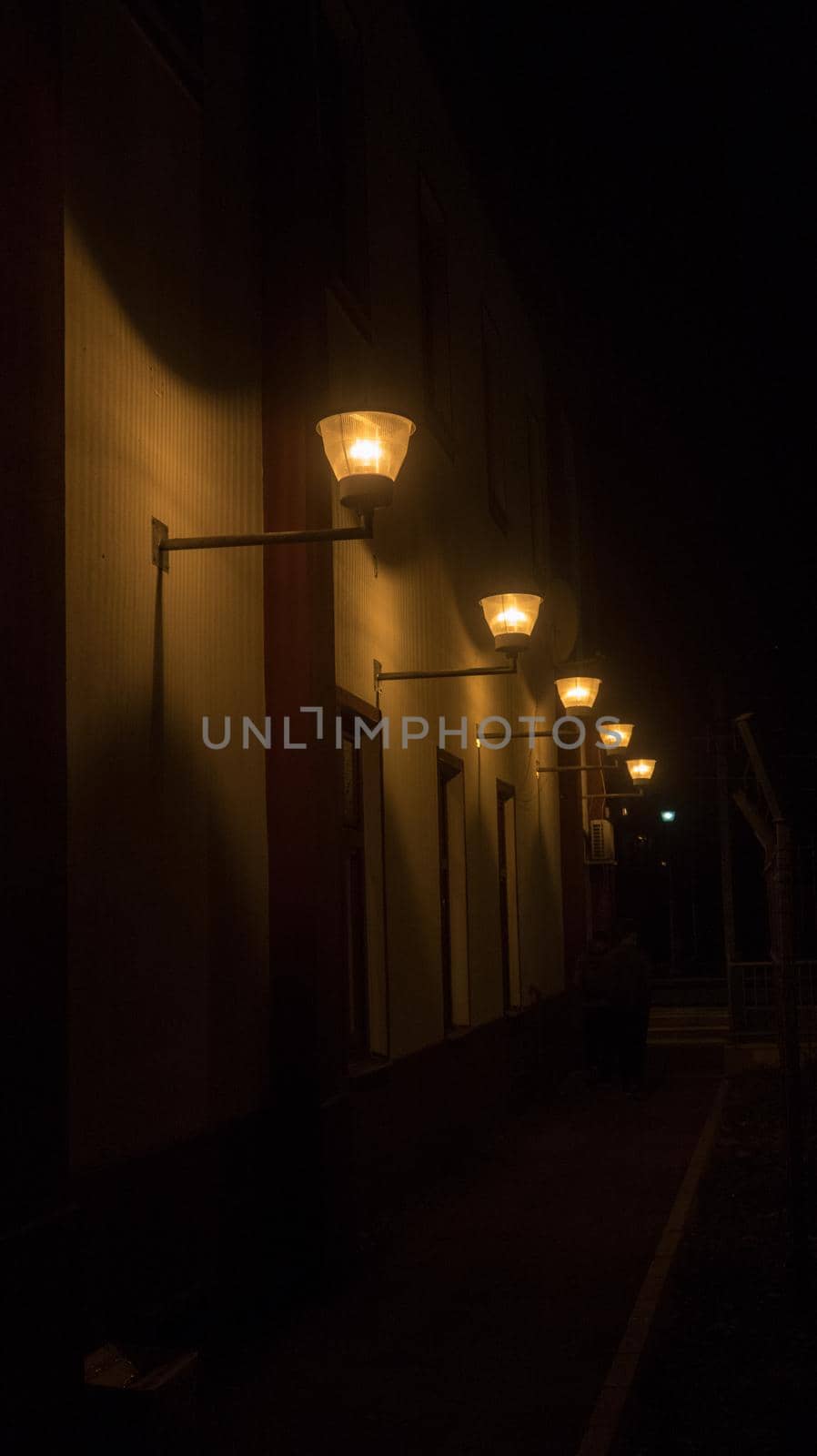 Yellow lamps on building shining at night by codrinn