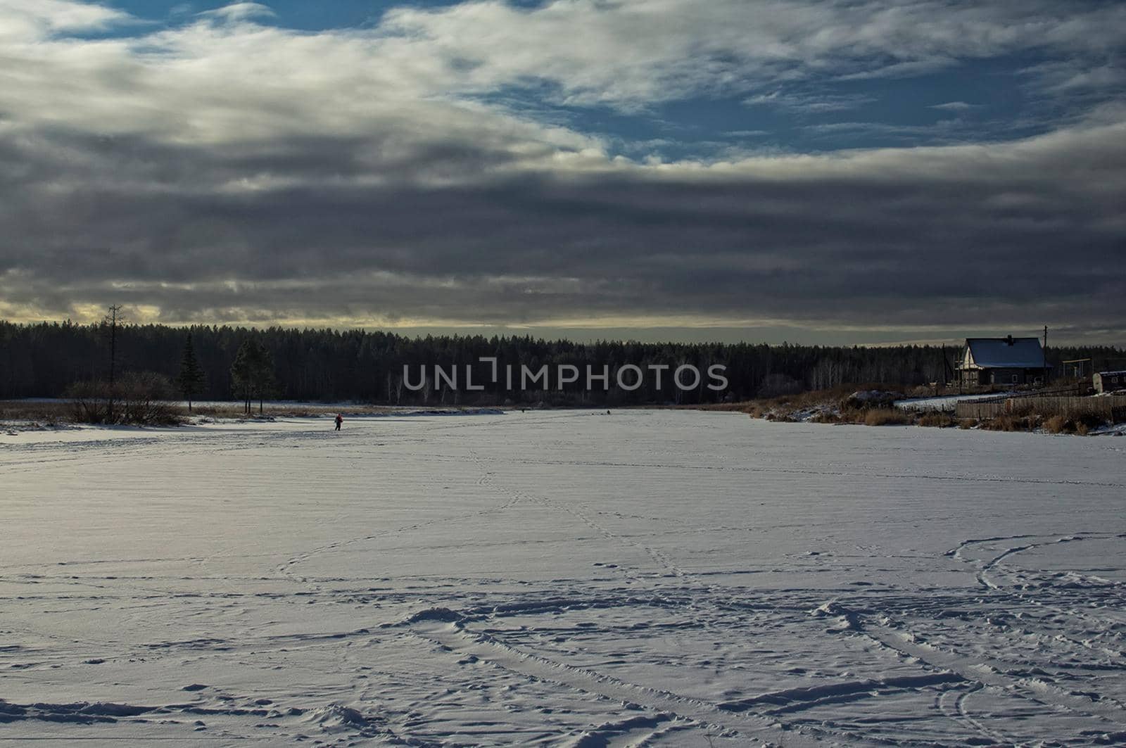 A house by a pond in winter in the snow. Life in nature by the water.