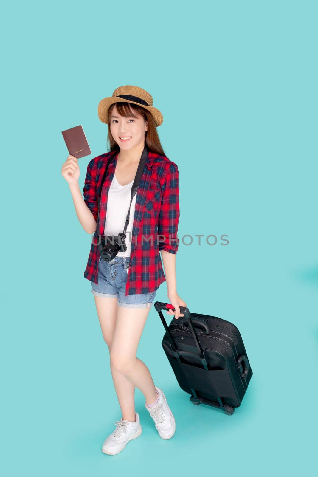 Beautiful young asian woman smiling and travel summer trip with luggage and holding passport for abroad in vacation, happy asia girl having camera walking and pull suitcase for journey in holiday.