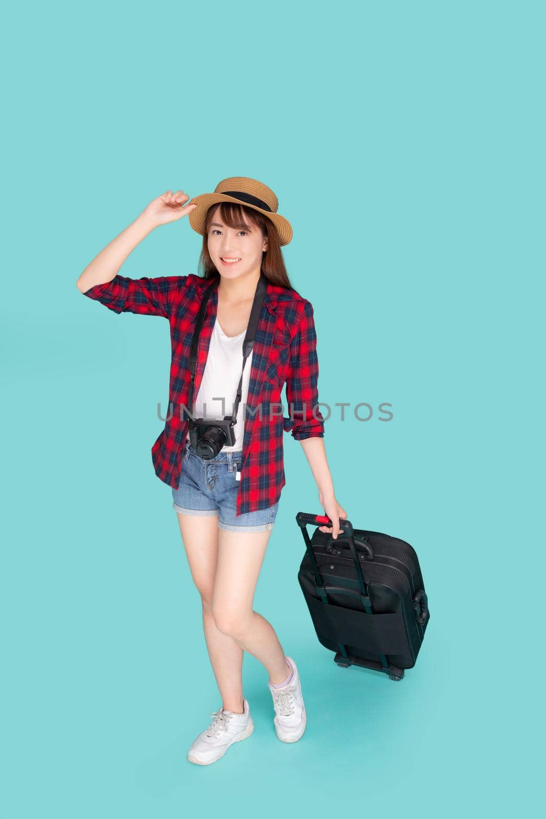 Beautiful young asian woman smiling and travel summer trip with luggage and holding hat for abroad in vacation, happy asia girl having camera walking and pull suitcase for journey in holiday.