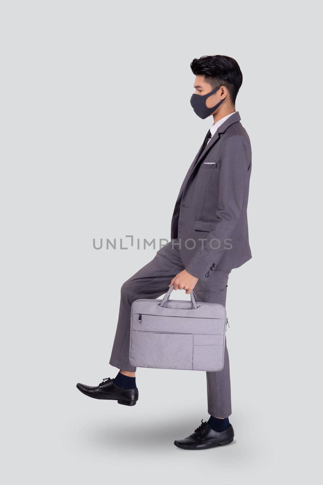 Portrait young asian businessman in suit wearing face mask walk step for protective covid-19 isolated on white background, business man and healthcare, quarantine for pandemic coronavirus, new normal.