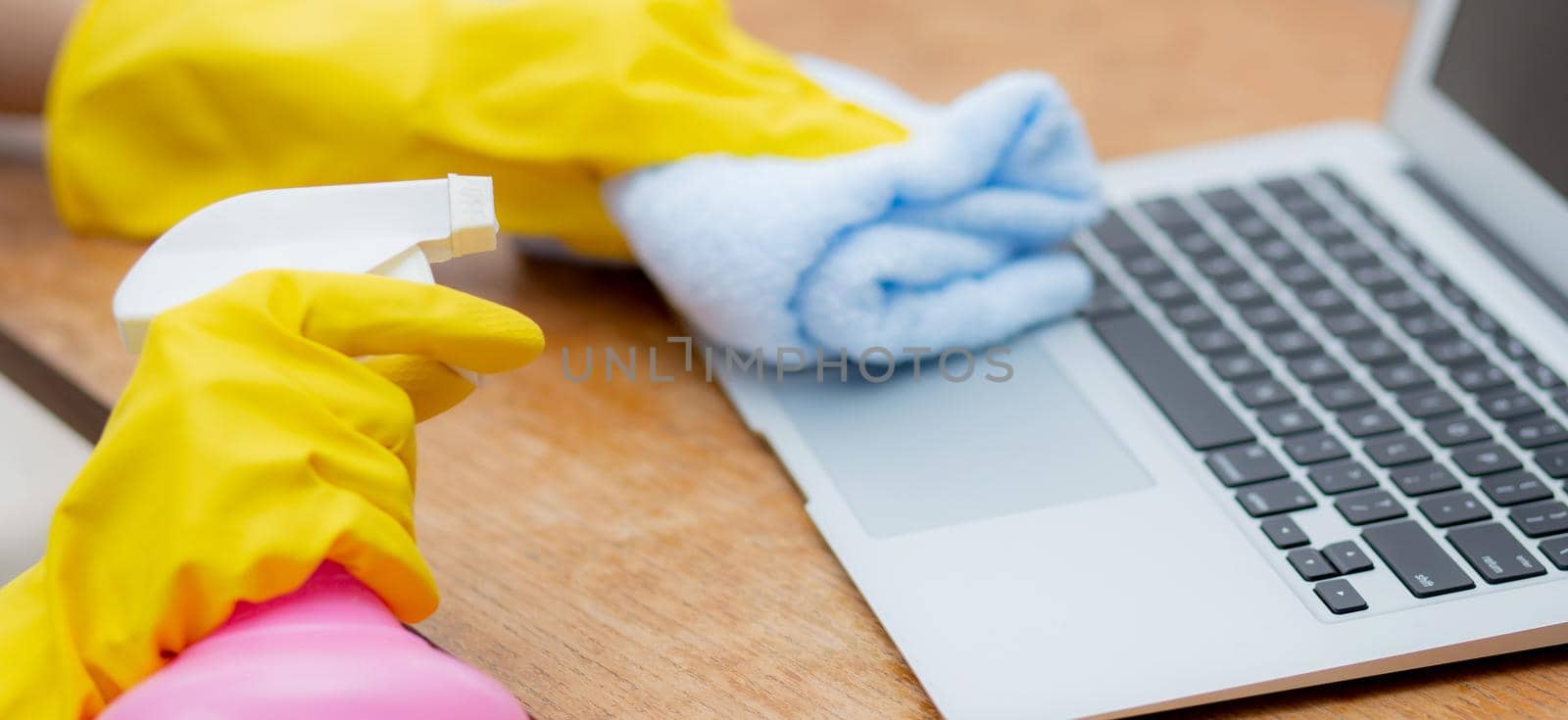 Hand of young asian woman cleaning and wipe laptop computer with disinfect and alcohol for protect pandemic covid-19 at home, girl in gloves cleaner notebook for hygiene, banner website.