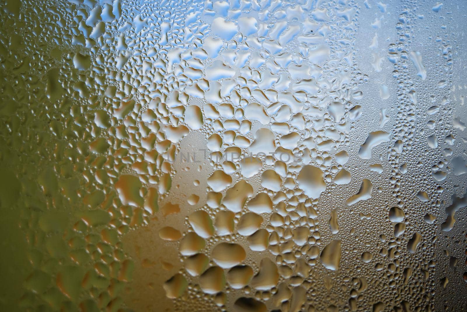 Condensation with beaded moisture droplets on the outside of a cold glass or bottle in a close up full frame background texture