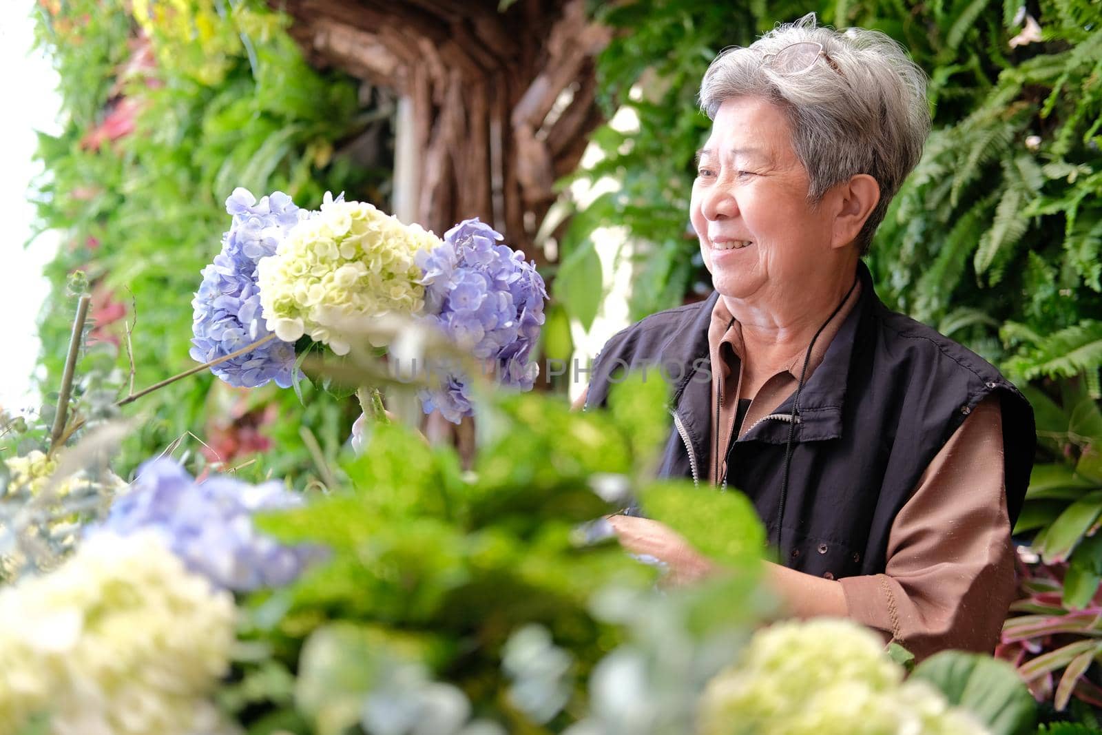 cheerful old asian elderly senior elder woman holding hydrangea flower bouquet