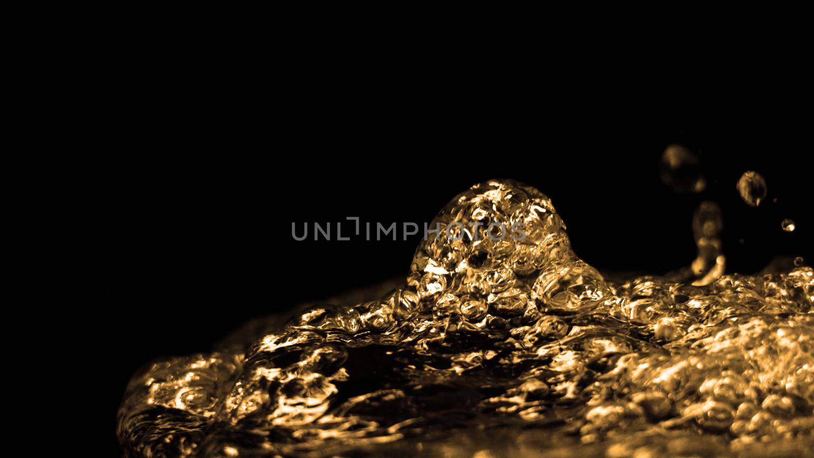 Hi speed close up images of oil liquid from diesel gasoline splashing and moving up to the air on black background for represent power of fuel liquid that active and powerful. studio shot premium gold color tone.