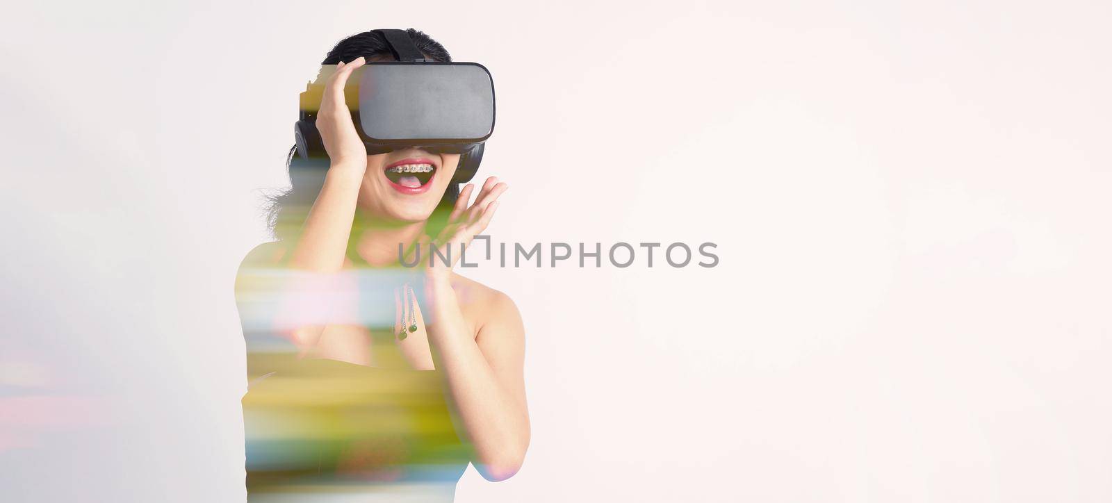 Asian teenage woman wearing VR or Virtual Reality head set and enter to the digital simulation world for learning and traveling or gaming  and more. Studio shot white background