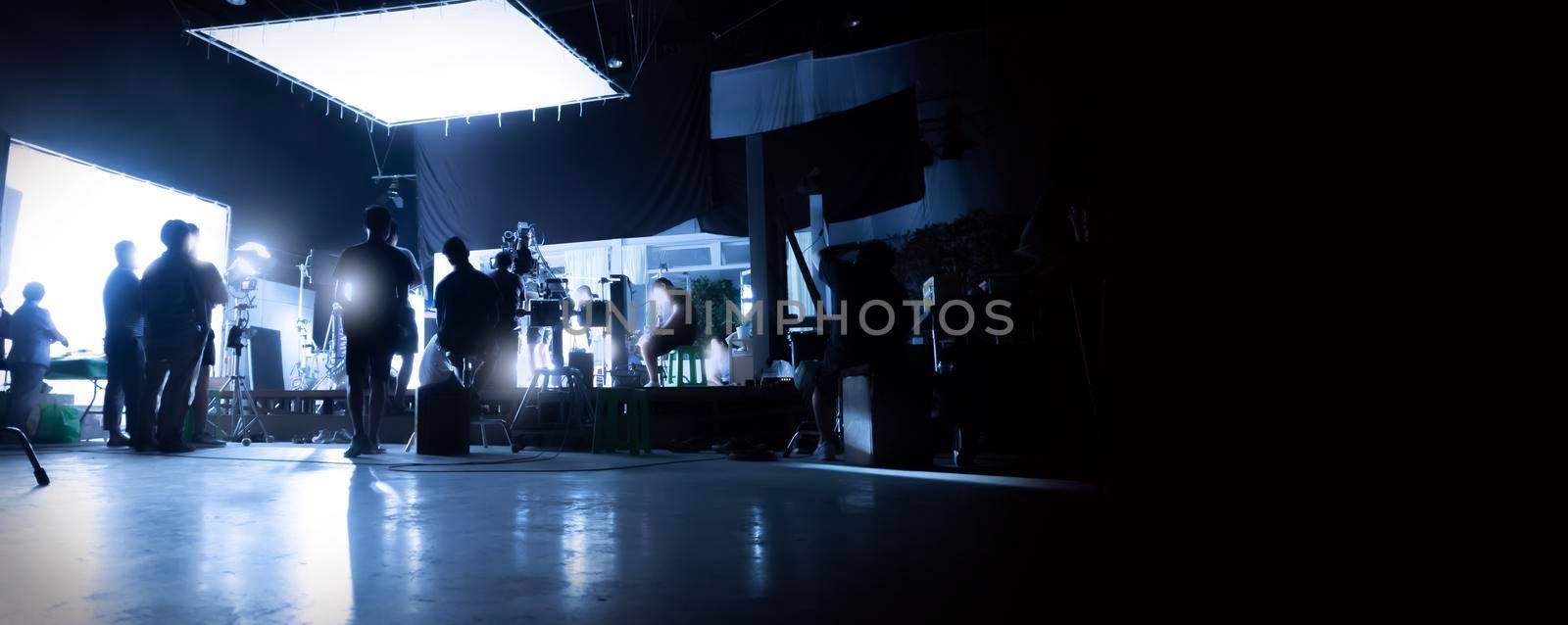 Silhouette images of video production behind the scenes or b-roll or making of TV commercial movies that film crew team lightman and videos cameraman working together with movie director in studio.