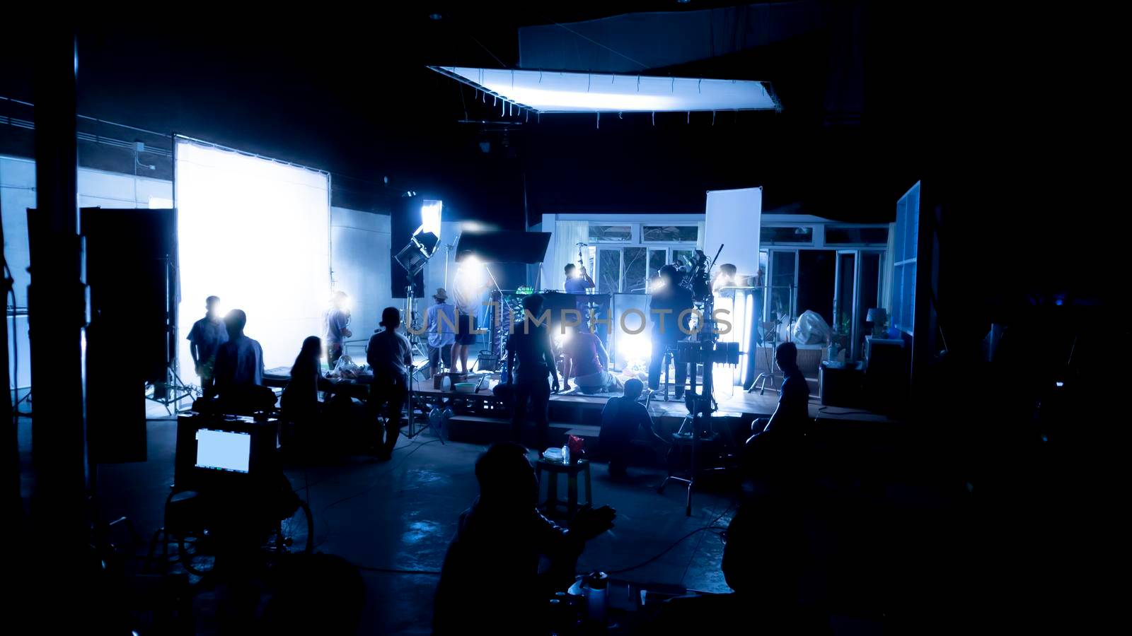 Silhouette images of video production behind the scenes or b-roll or making of TV commercial movies that film crew team lightman and videos cameraman working together with movie director in studio.