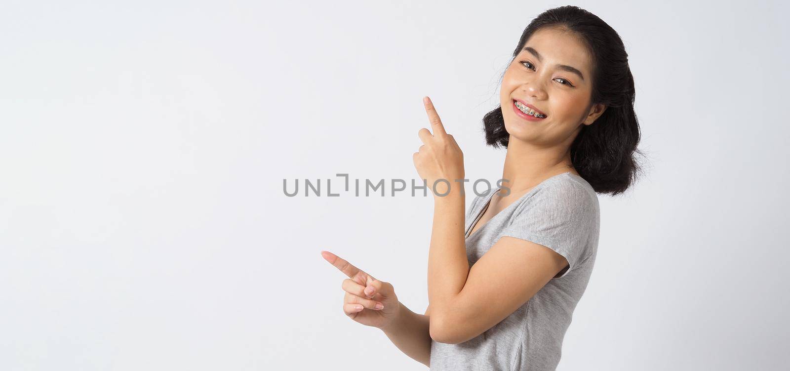 Dental brace beautiful girl smiling looking on a camera. white teeth with blue braces. Dental care. Asian teen woman smile with orthodontic accessories. Cosmetic dentistry, orthodontics treatment. white background studio.