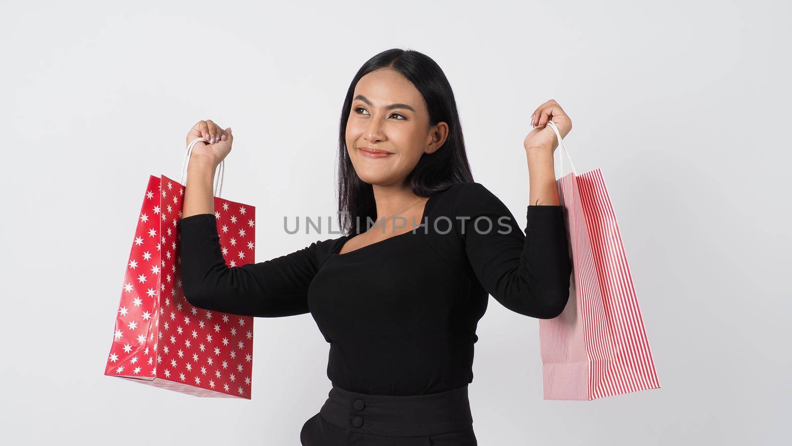 Happy shopping concept. Young asian Thai woman in action or activity of purchasing goods from stores or online shop. Happily girl and shopping bags during sale season in studio white background