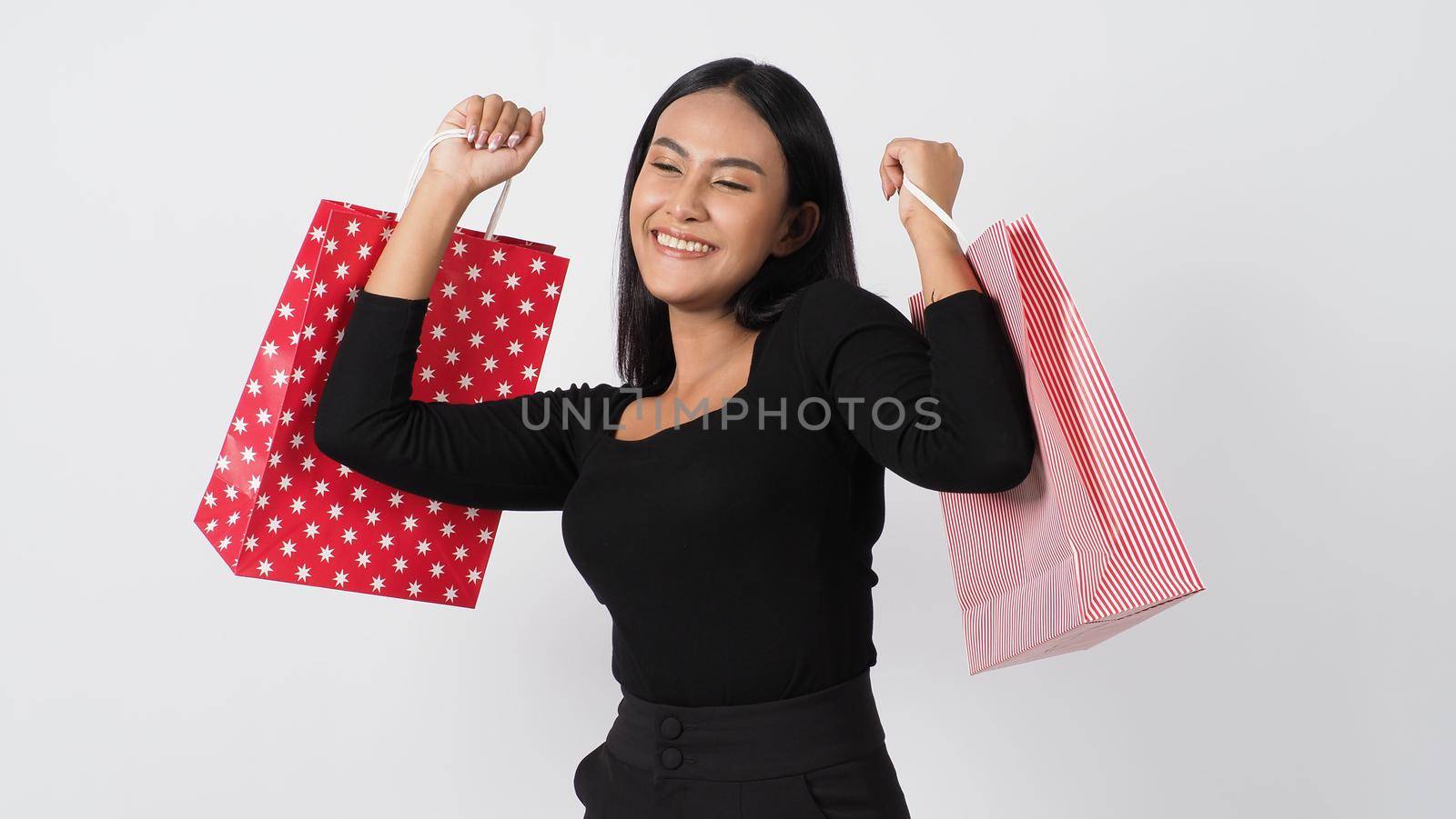 Happy shopping concept. Young asian Thai woman in action or activity of purchasing goods from stores or online shop. Happily girl and shopping bags during sale season in studio white background