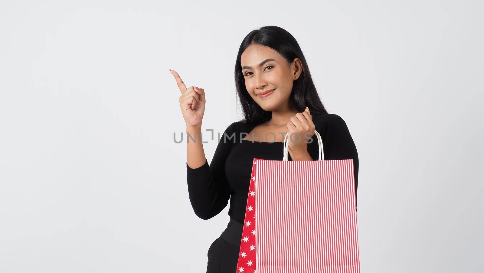 Happy shopping concept. Young asian Thai woman in action or activity of purchasing goods from stores or online shop. Happily girl and shopping bags during sale season in studio white background