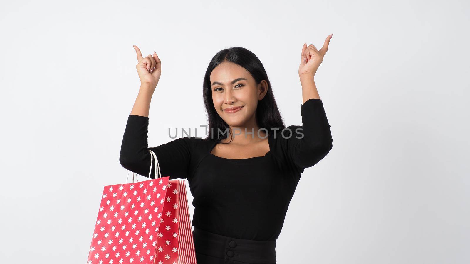 Happy shopping concept. Young asian Thai woman in action or activity of purchasing goods from stores or online shop. Happily girl and shopping bags during sale season in studio white background