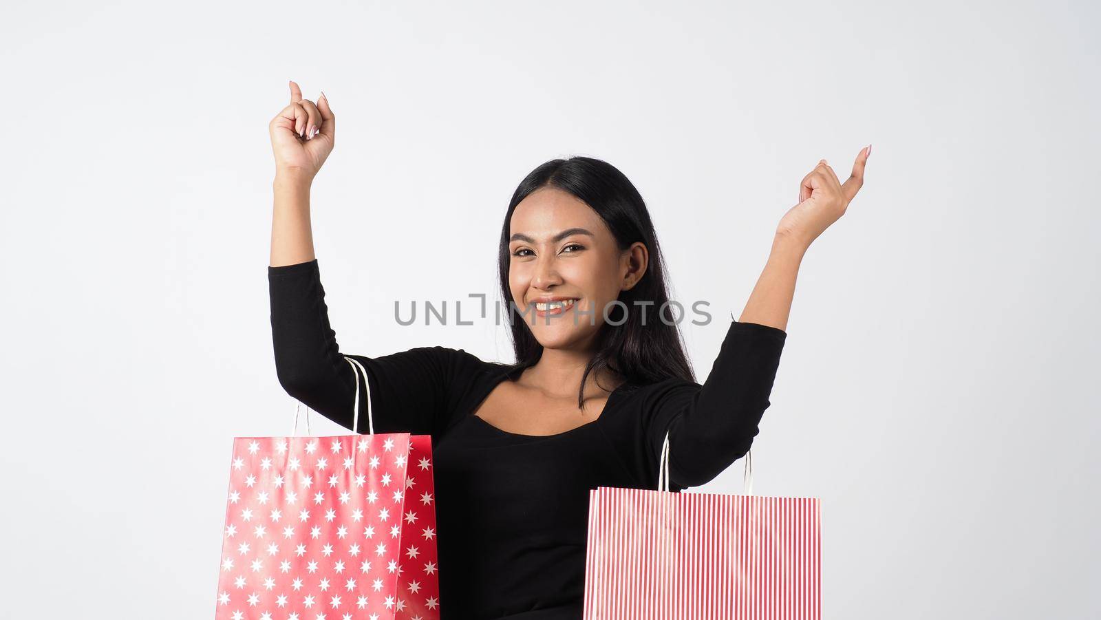 Happy shopping concept. Young asian Thai woman in action or activity of purchasing goods from stores or online shop. Happily girl and shopping bags during sale season in studio white background