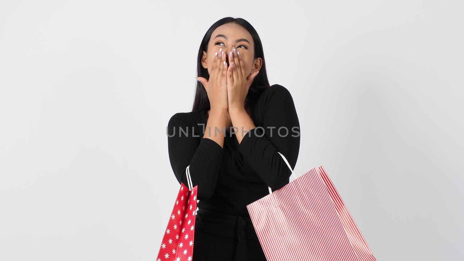 Happy shopping concept. Young asian Thai woman in action or activity of purchasing goods from stores or online shop. Happily girl and shopping bags during sale season in studio white background