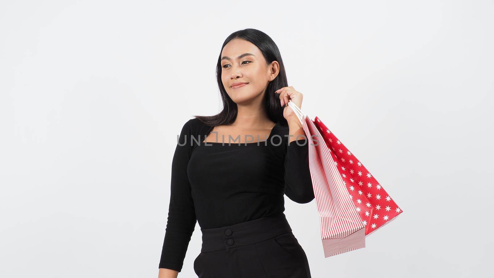 Happy shopping concept. Young asian Thai woman in action or activity of purchasing goods from stores or online shop. Happily girl and shopping bags during sale season in studio white background