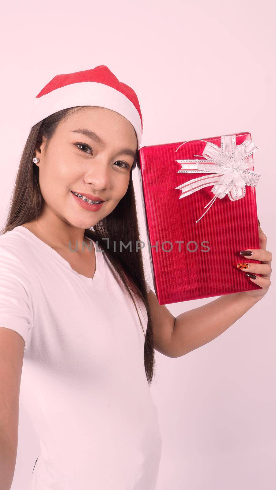 Girl hold gift box make selfie or video online with x-mas christmas prop decoration. Asian Thai teen woman taking online-selfie to celebrate festive season with her friend by red giftbox. studio shot.